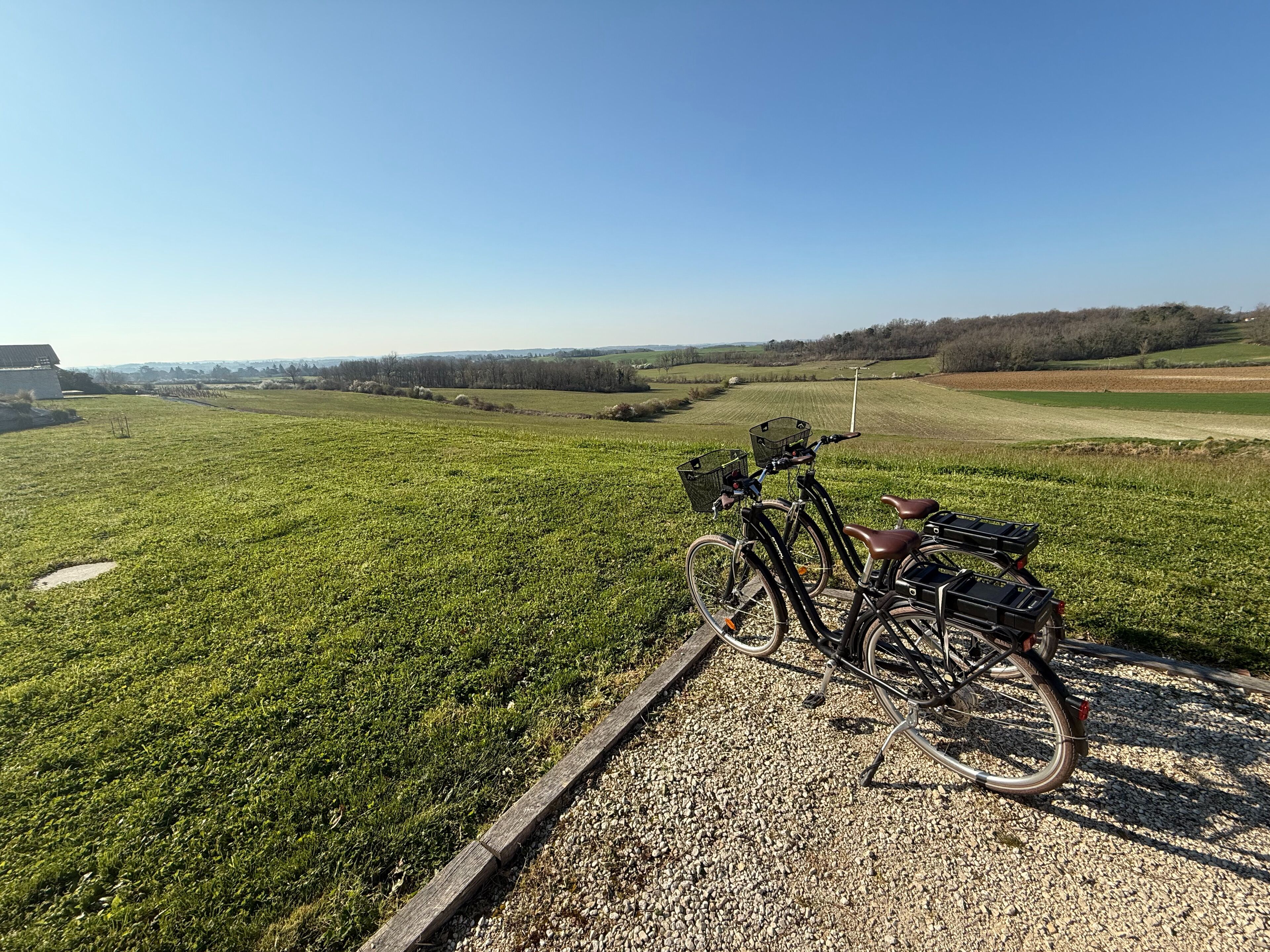 A bicycle parked on a gravel path with a scenic view of a green field and distant hills.