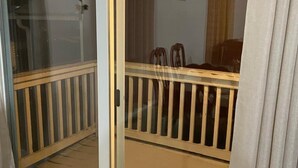 A room with a sliding glass door leading to a balcony with a wooden railing.