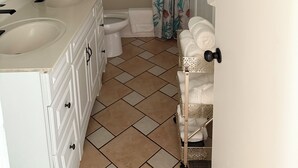 A bathroom with two sinks, a toilet, a shower with a curtain, and a towel rack.