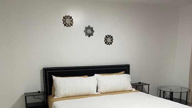 A bedroom with a large bed, two bedside tables, and decorative wall mirrors.