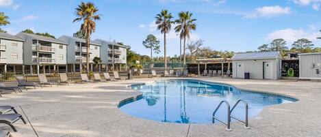 A swimming pool with lounge chairs and a building with balconies.