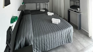 Une chambre d’hôtel équipée d’un lit superposé, d’un bureau avec une chaise, d’un téléviseur à écran plat, d’un climatiseur et d’un miroir.