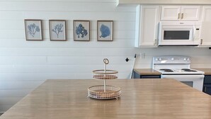 Eine moderne Küche mit Holztisch, weißen Schränken und einem Einbauofen.
