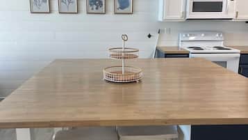 Una cocina moderna con una mesa de madera, armarios blancos y un horno empotrado.