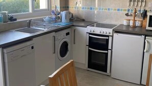 A compact kitchen with a washing machine, oven, and microwave.