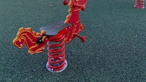 A playground with a slide, climbing structures, and a red horse ride.