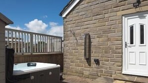 A patio area with a hot tub, a wooden deck, and a stone wall. - Cricketers View - West Yorkshire (Bradford)