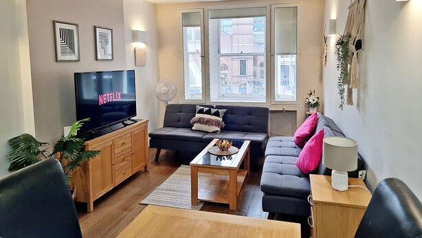 A modern living room with a flat-screen TV, two sofas, a coffee table, and a wooden cabinet. - Liverpool Street Apartments (London)