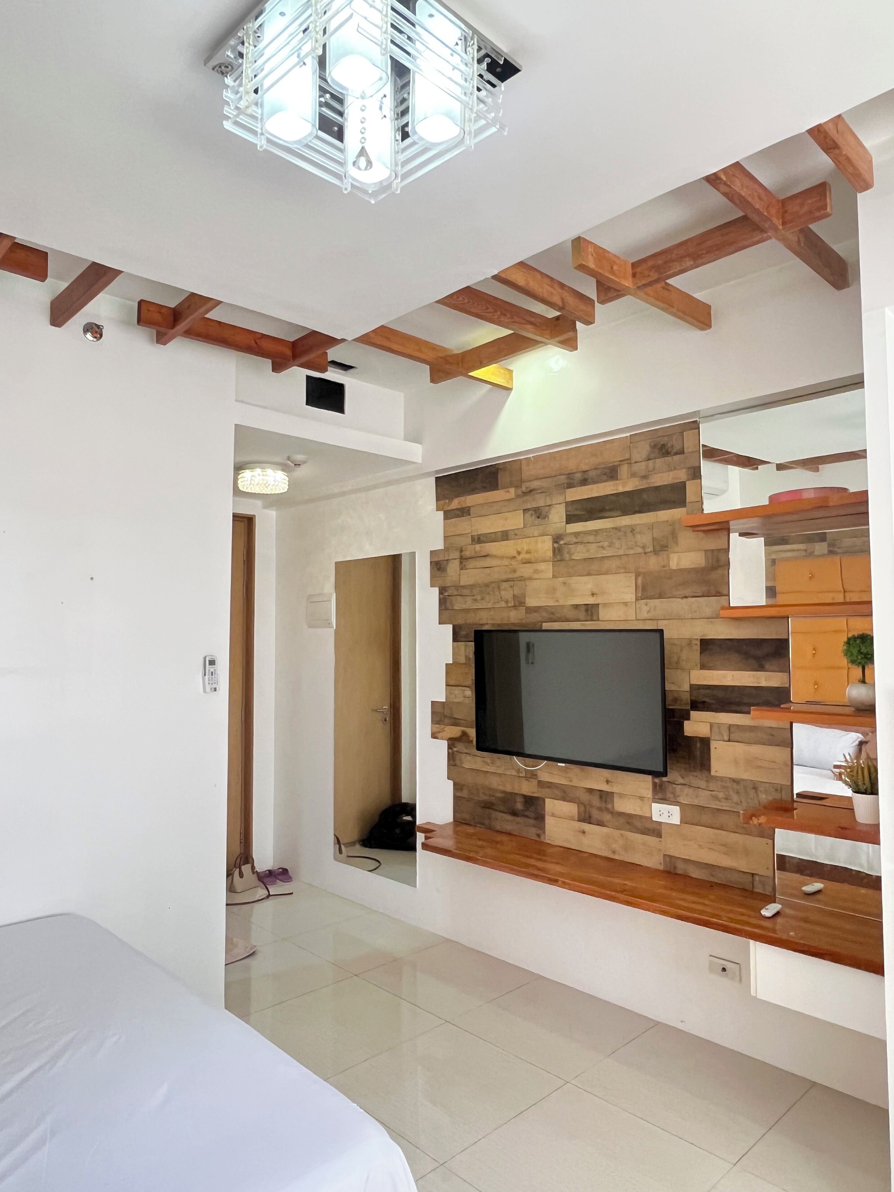 A modern room with a wooden ceiling, a mounted TV, and built-in shelves.