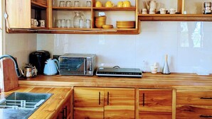 Een keuken met houten kastjes, een aanrecht en diverse keukenapparaten.