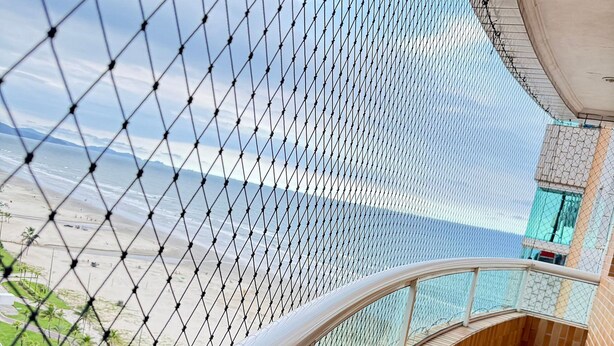 Un balcon incurvé offrant une vue sur une plage et des palmiers.