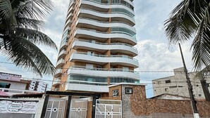 Un immeuble moderne et imposant, doté d’une façade incurvée, de nombreux balcons et d’une entrée sécurisée par un portail.