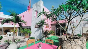 An outdoor seating area with a pink table and chairs, surrounded by potted plants and a stone wall. - Hotel Don Luis  (Valladolid)