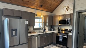 Una cocina moderna con electrodomésticos de acero inoxidable, techo de madera y un detalle decorativo rústico.