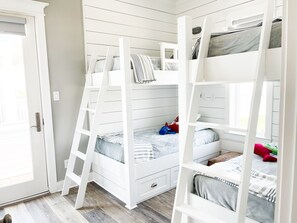 A room with two bunk beds, a door, and a window.