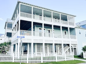 A multi-story building with balconies, a covered porch, and a white picket fence. - Beautiful decorated family home on the beach (Galveston)