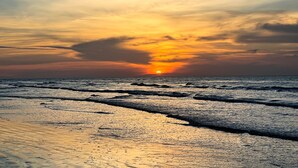 A sunset over a beach with waves and a clear sky. - Beautiful decorated family home on the beach (Galveston)