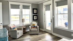 A spacious room with a high ceiling, large windows, and a ceiling fan. - Beautiful decorated family home on the beach (Galveston)