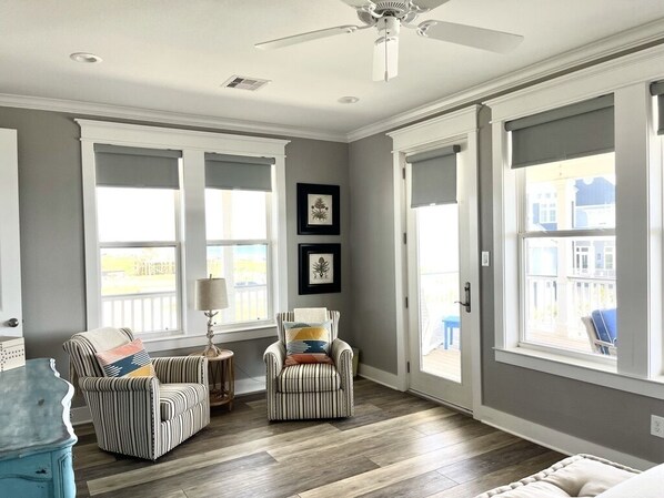 A spacious room with a high ceiling, large windows, and a ceiling fan.