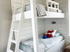 Ein Stockbett mit einer Leiter, einem Fenster und einem Stofftier auf der unteren Liege.