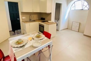 Enjoy meals in this cozy kitchen with a dining table for two, featuring a sink, stove, and ample natural light.