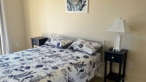 A bedroom with a bed, a nightstand, a lamp, and a wall art piece.
