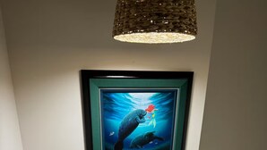 A framed artwork of an underwater scene with a mermaid and a manatee, hanging on a wall.
