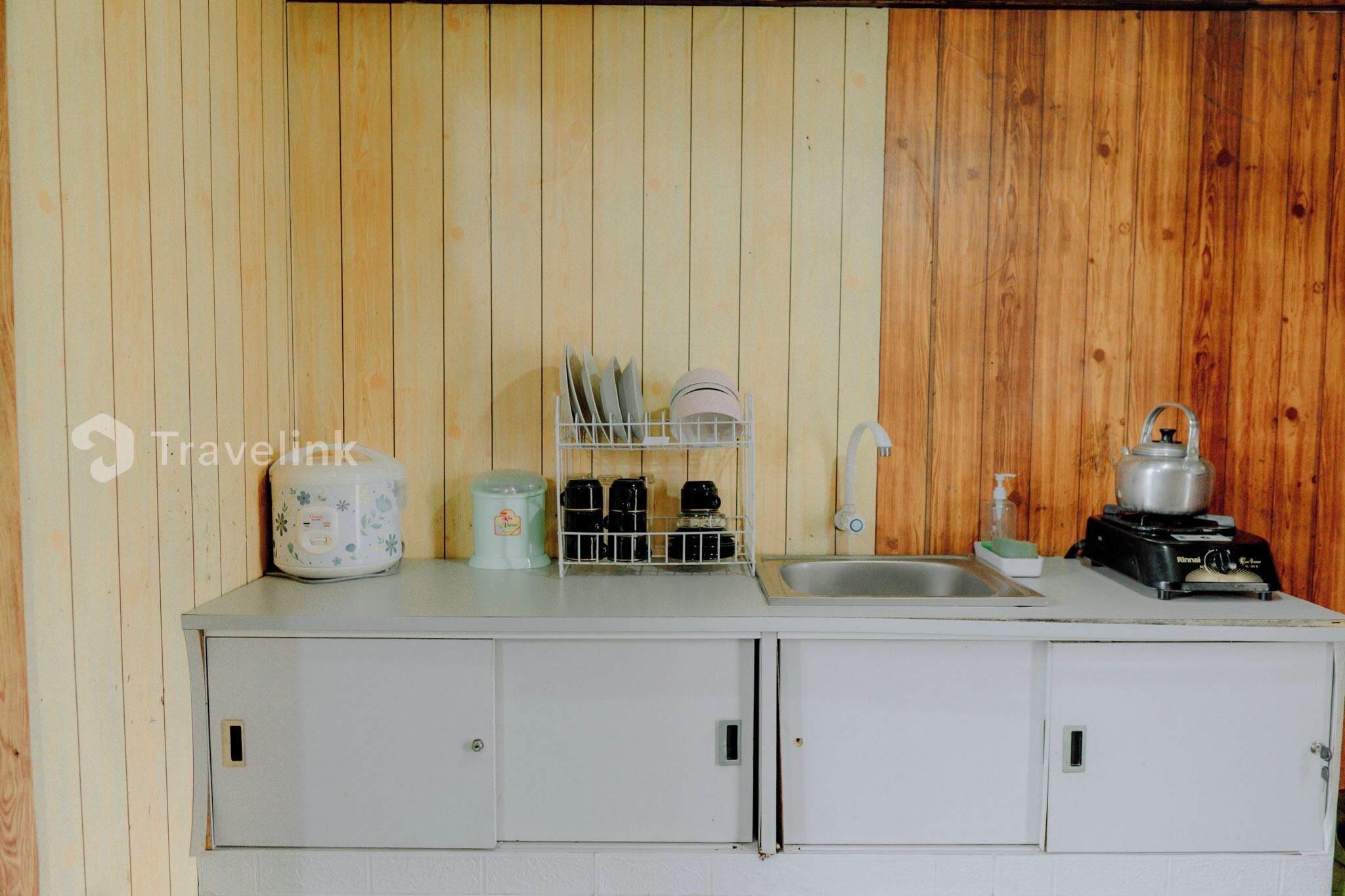A compact kitchenette with a sink, a stove, and a dish rack.