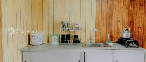 A compact kitchenette with a sink, a stove, and a dish rack.
