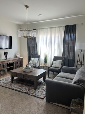 A modern living room with a wooden coffee table, two grey sofas, a TV, and a chandelier. - Enjoyable Guest Suite in Lancaster (Lancaster)
