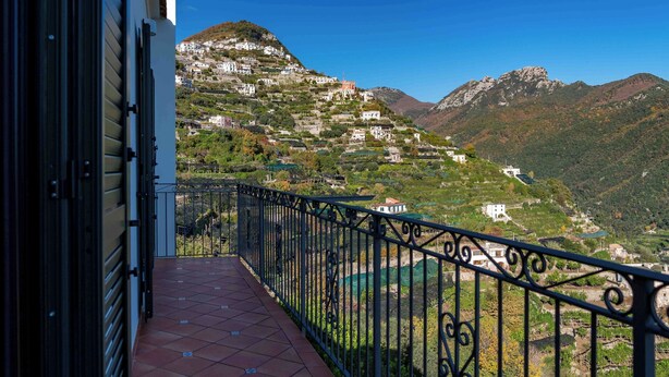 A balcony with a view of a hillside village and mountains.