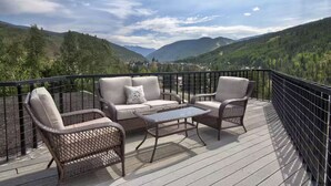 A deck with wicker furniture, a glass table, and a scenic mountain view. - Vail Run 4 Bed room Spring Break Week with Heated Pool, Hot Tub, Sauna (Vail)