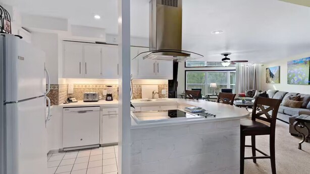 A modern kitchen with white cabinetry, a central island, and a dining area with a sofa and chairs. - Vail Run 4 Bed room Spring Break Week with Heated Pool, Hot Tub, Sauna (Vail)