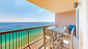 Un balcon avec vue sur l’océan, une table et deux chaises.