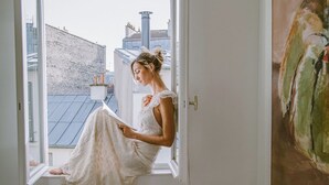 Une pièce avec une grande fenêtre, une chaise et un tableau accroché au mur.