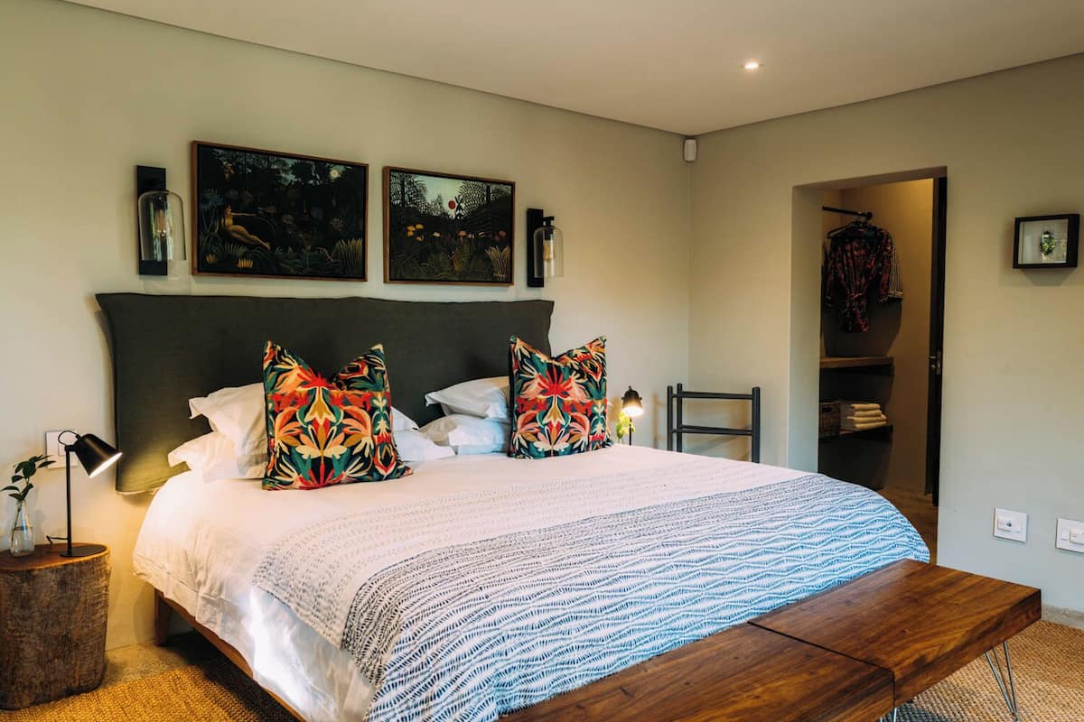 A neatly arranged bedroom with a large bed, two side tables, a bench, and a wardrobe.