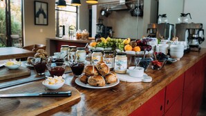 A breakfast buffet with various spreads, fruits, and pastries on a wooden counter. - Phakalane Retreat (Cape Town)