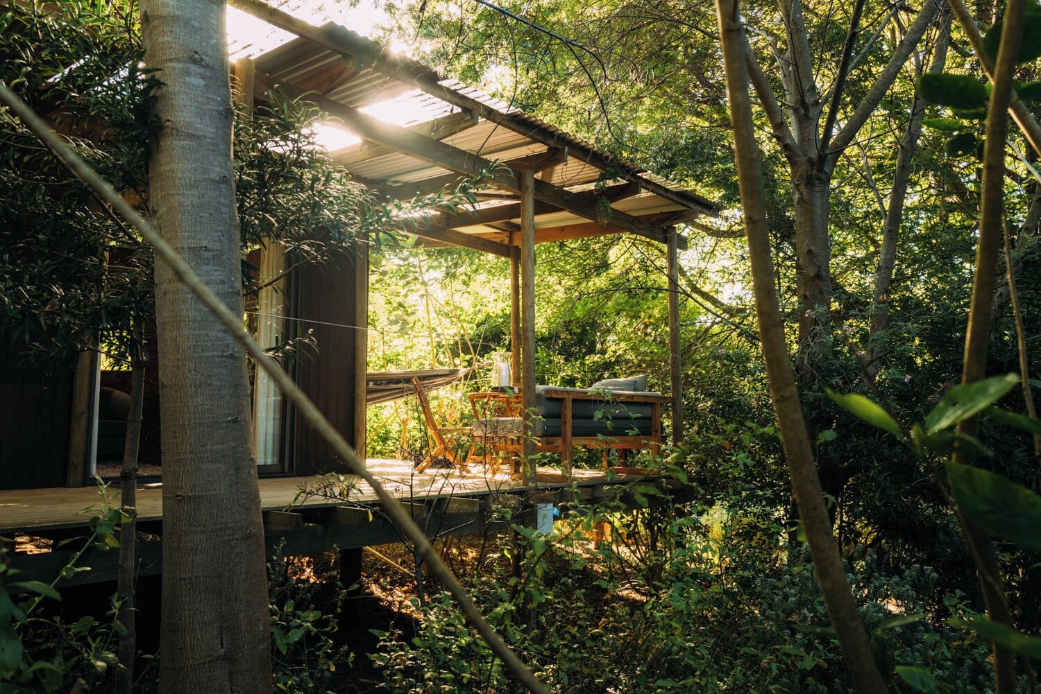 A wooden treehouse with a wooden deck and a covered seating area.
