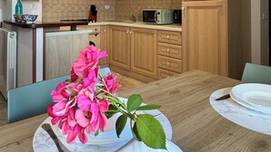 Una cocina moderna con armarios de madera, una mesa de comedor con un jarrón de flores y un microondas.