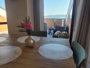 Una mesa de comedor con un florero, vistas al exterior y una pared de ladrillo.
