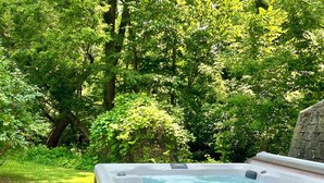A hot tub in a garden with a stone pathway leading to it. - Charming 2-bedroom house in serene Coloma with AC, WiFi (Coloma)