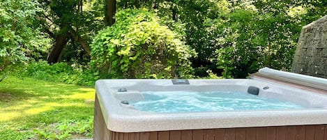 A hot tub in a garden with a stone pathway leading to it.