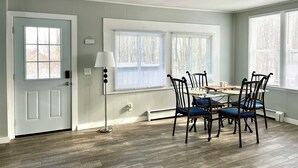 A dining area with a table and chairs, a floor lamp, and a door with a window. - Charming 2-bedroom house in serene Coloma with AC, WiFi (Coloma)