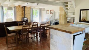 Una cocina amplia con comedor, paredes de piedra y una escalera que sube a un nivel superior.