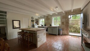 Una cocina amplia con una isla grande, electrodomésticos integrados y vistas a través de una puerta corrediza de vidrio.