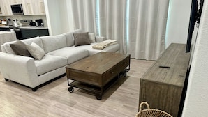A modern living room with a sofa, coffee table, and a small wooden side table. - Charming 3-bedroom House in Queen Creek w/ Community Pool (Queen Creek)