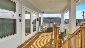 Une véranda couverte avec une terrasse en bois, des portes-fenêtres coulissantes et du mobilier d’extérieur.