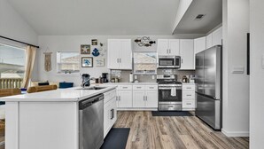 Une cuisine moderne avec des meubles blancs, des appareils en acier inoxydable et un plancher en bois.