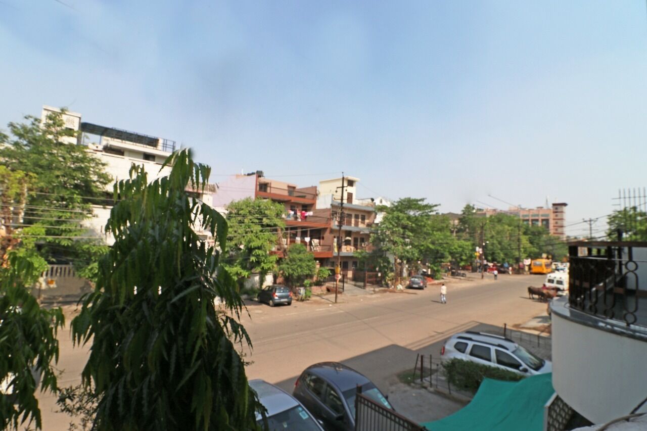 A street view with buildings, parked cars, and trees.