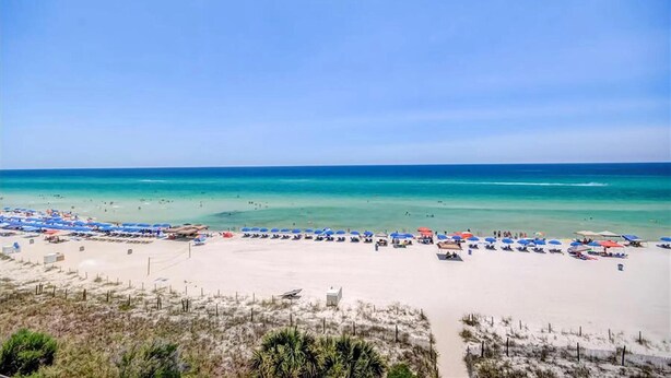 A beach with numerous umbrellas and beachgoers. - Laketown Wharf 1116 (Panama City Beach)